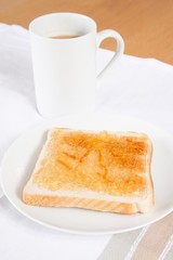 Jam on slice of bread with cup of coffee