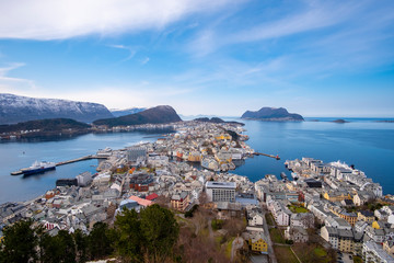 birds eye, aerial view over scandinavian city of Alesund and Harbor with a beautiful sight of the fjord of Alesund on a sunny day in spring with blue skies