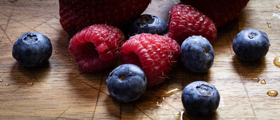 Blueberries, raspberries and strawberries on a wooden bord, kitchen concept healthy fresh food, newly washed