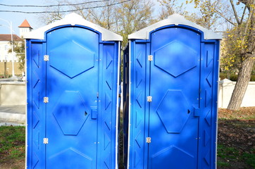 Two blue street toilets are next to each other.