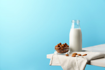 Glass reusable bottle with almond milk, almond nuts lie nearby, textile napkin on a white wooden...