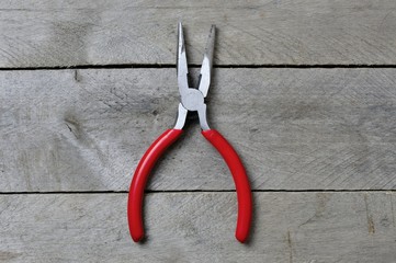 pliers with red handles on a wooden background