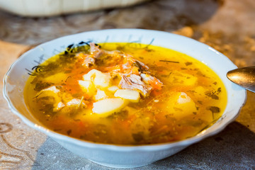 Bowl of traditional chicken soup on kitchen table close