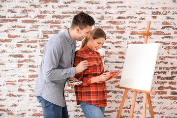 Couple of young artists against brick wall