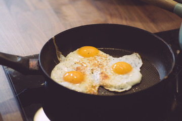 Fried eggs in the pan for breakfast. Cooking breakfast with fried eggs and toast in the kitchen