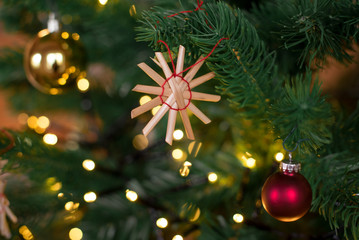 christbaumanhaenger strohstern nahaufnahme im weihnachtsbaum haengend hochformat