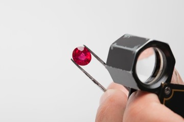Close up of red gemstone in tweezers