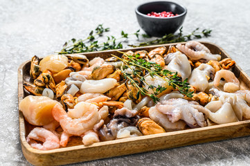 Raw sea seafood cocktail in a wooden bowl. Gray background. Top view
