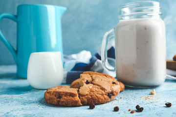 Tasty cookies with chocolate chips and milk on table