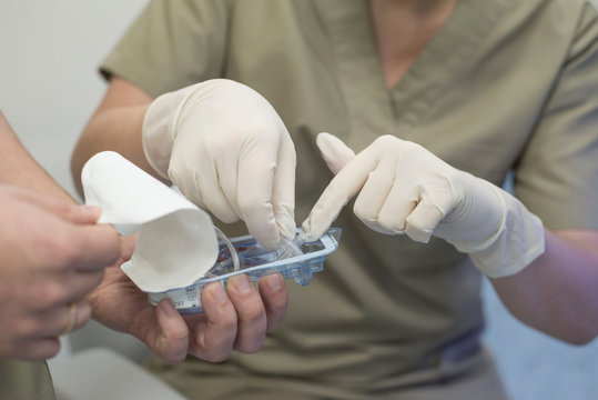 close-up of the hands of an ophthalmologist surgeon with the help of the hands of an assistant surgeon takes a sterile instrument for laser eye surgery from the packaging
