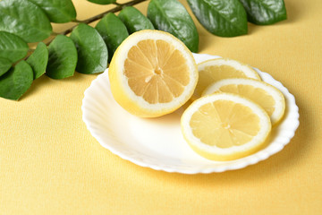 Juicy lemon on a white plate on a yellow background