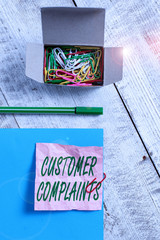 Conceptual hand writing showing Customer Complaints. Concept meaning expression of dissatisfaction on a consumer s is behalf Wrinkle paper and cardboard placed above wooden background