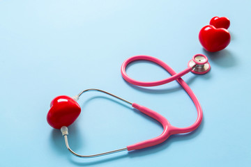 Stethoscope and red hearts on color background. Cardiology concept