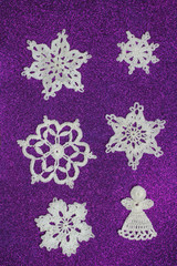 Snowflake knitted from white threads on a purple background. Handmade
