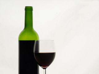 Close up of red wine glass with a bottle of red wine