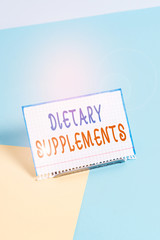 Text sign showing Dietary Supplements. Business photo showcasing Product taken orally intended to supplement ones diet Paper placed tilted above buffer wire on soft pastel multi colours backdrop