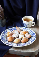 Lavender madeleines on a porcelain plate on a blue background. Rustic style.