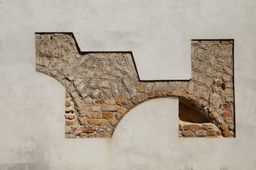 Ancient stone and brick wall with arched openings intentionally partially exposed after being covered with new paintwork. In Vilnius, Lithuania.