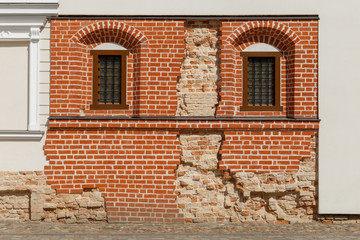 Ancient brick wall of a historical house intentionally partially exposed after being restored and covered with new facade. In Vilnius, Lithuania.