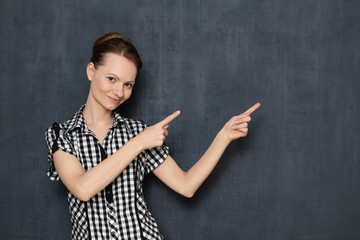 Portrait of happy young woman pointing at copy space on right