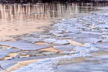 Ice on the river during the ice drift lit by the setting sun in the spring	