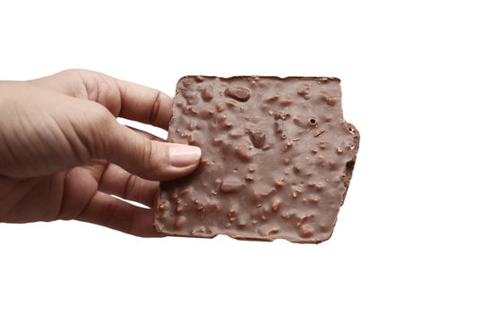 Broken bar of brown, milk chocolate with nuts in a female hand on a white background. Isolated with tinted.