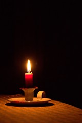 Candle light on a table, shining in the dark. Power outage, blackout concept background.