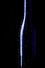 Elegant blue bottle of expensive wine gift with drops of water on a black background isolated