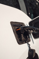 Tramsportation. Elcetric car close-up at charging station no people charging with EV charger in...