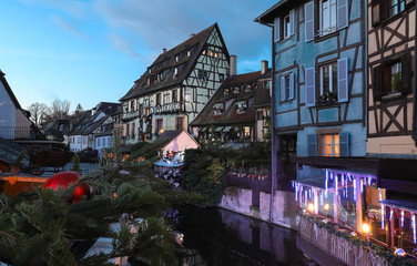 Fototapeta na wymiar Traditional Alsatian half-timbered houses in old town of Colmar and branches of Christmas tree in the foreground.