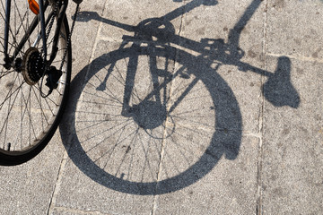Naklejka na ściany i meble Rear wheel of a bicycle and its shadow on the pavement.
