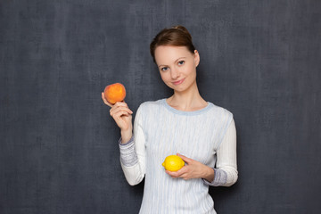 Portrait of happy girl smiling and holding lemon and peach in hands