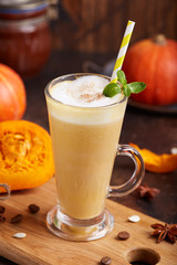 Spiced pumpkin latte. Delicious season beverage with coffee, pumpkin syrup, whipped cream and cinnamon. Rustic style.