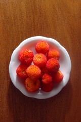 Irish strawberries (Arbutus unedo) served on a dish on a wooden table.