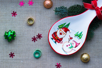 Christmas decorations. Decorative white tableware with the image of Santa Claus, snowman and Christmas trees. Chocolates in festive packaging. Ribbon for decoration. Christmas background.