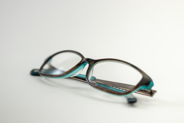 A pair of modern female reading glasses isolated in a studio shot black and turquoise colored frames prescribed from a profession optometrist with isolated white background 