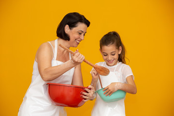 Mother's day concept! Daughter and mother preparing a recipe on yellow background