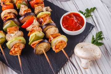 chicken kebabs with vegetables and mushrooms on a rustic background