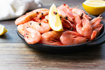 Tasty organic shrimps with spices and lemon in a pan on dark wooden table close up. Sea food concept. Healthy and organic food concept.