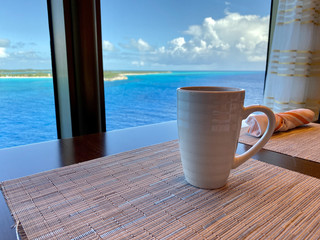 Coffee on a table aboard a cruise ship overlooking the beautiful turquoise waters of the Bahamas.