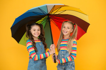 No more rain. Good mood at any weather. small girl under colorful umbrella. two happy kids yellow wall. children enjoy rainy autumn. fall kid fashion. feeling safe and comfortable. Autumn beauty