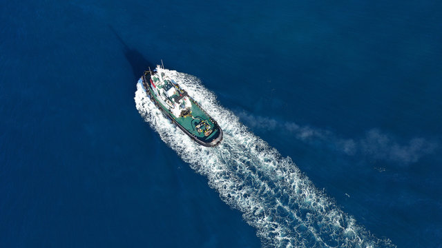 Aerial drone top down photo of tug boat cruising Mediterranean port