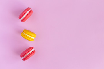 Three tasty french macarons on pink background. Pink and yellow macarons.
