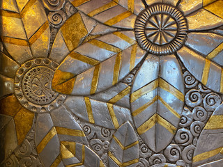 Gold and silver floral design on a wall that can be used as a background for graphic design.