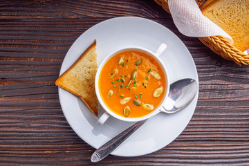 pumpkin cream soup on rustic wooden background