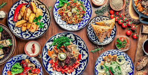 Fototapeta na wymiar Traditional Uzbek oriental cuisine. Uzbek family table from different dishes for the New Year holiday. The background image is a top view.