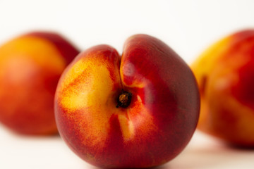 One nectarine on a background of two nectarines on a white background
