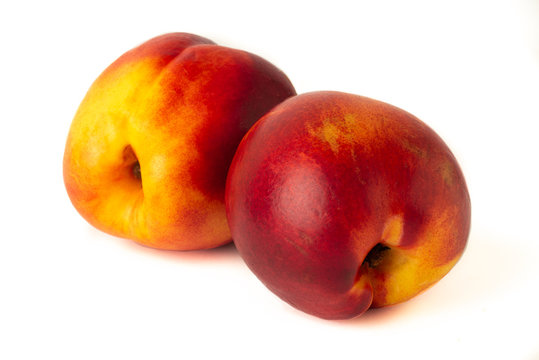 Two juicy orange nectarines close-up on a white background