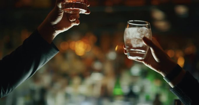 Close up of two people are cheering with cocktails in a bar or disco club.
