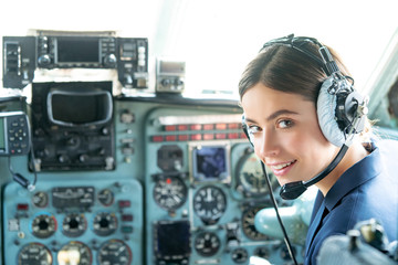 Happy and successful flight. Smiling female pilot in the aircraft , she is holding aviator headset and looking at camera. Wishes a successful fligh. © Nikoletta